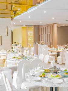 a dining room with white tables and white chairs at Srilamduan Hotel in Si Sa Ket