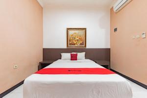 1 dormitorio con 1 cama blanca grande con manta roja en RedDoorz near Kejaksan Station Cirebon, en Cirebon
