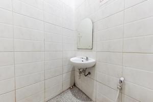 Baño blanco con lavabo y espejo en RedDoorz near Kejaksan Station Cirebon, en Cirebon