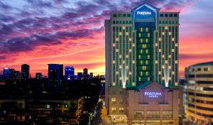 a view of a tall building with a sunset in the background at Fortuna Hotel Hanoi in Hanoi