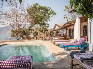 a swimming pool with lounge chairs next to a house at Thumbi View Lodge in Cape Maclear