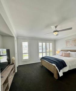 a white bedroom with a bed and a ceiling fan at Hillston House in Kiama