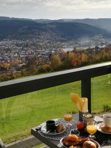 a table with food and drinks on a balcony with a view at Duplex Estelle - 2 couples ou famille in Gérardmer