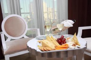 uma mesa com uma bandeja de queijo, uvas e taças de vinho em Amber Hotel em Baku