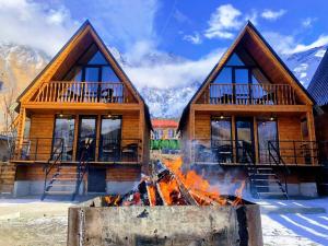 a log cabin with a fire in front of it at Cottage Caucasus in Stepantsminda