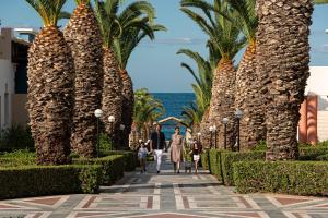 een familie die over een loopbrug tussen palmbomen loopt bij Aldemar Knossos Royal in Chersonissos