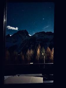 una ventana con vistas a una montaña por la noche en IL COVO DELLO SCIATORE, en Falcade
