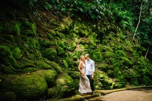 a bride and groom standing in front of a rock wall at Ayung Resort Ubud in Payangan