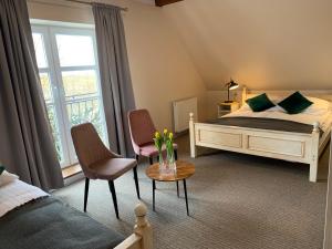 a bedroom with a bed and two chairs and a window at Dworek Golikowo in Sławno