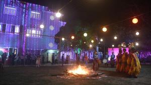 Un groupe de personnes debout autour d'un feu de camp la nuit dans l'établissement Jhargram Eshani Hotels and Guest House, à Jhārgrām