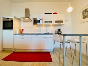 a kitchen with white cabinets and a red rug at Villa Anna App. 7 Seeblick in Heringsdorf +10 photos