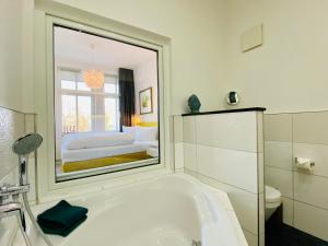 een badkamer met een bad, een toilet en een spiegel bij Villa Anna App. 7 Seeblick in Heringsdorf