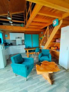 ein Wohnzimmer mit blauen Stühlen und einem Holztisch in der Unterkunft Gîte avec piscine jacuzzi espace bien-être partagés entre Bordeaux et Lacanau océan in Brach