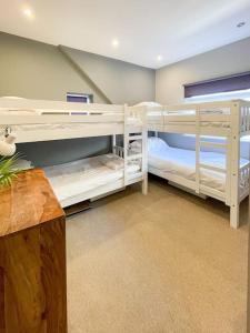 two white bunk beds in a room at Edge14- spacious, stylish and near the beach! in Newquay