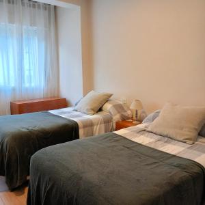 two beds in a room with a window at Pensión Fornos in Caldas de Reis