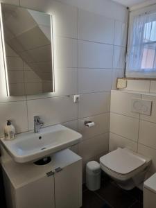 a white bathroom with a sink and a toilet at Ferienhaus 10 in Tossens in Tossens