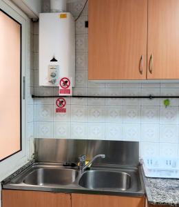 a kitchen with a stainless steel sink and wooden cabinets at Pensión Fornos in Caldas de Reis