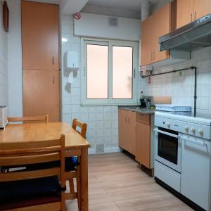 a kitchen with a wooden table and a table and a dining room at Pensión Fornos in Caldas de Reis