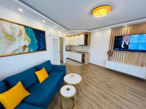 un salon avec un canapé bleu et une télévision dans l'établissement GRAND LUX Apartment, à Doboj