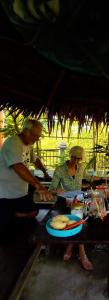 a couple of people preparing food at a table at Raja Ampat Sandy Guest House in Saonek