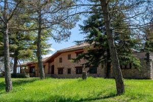 una casa de piedra con árboles delante de ella en Lodging Apartments Villa el Raco, en Santpedor