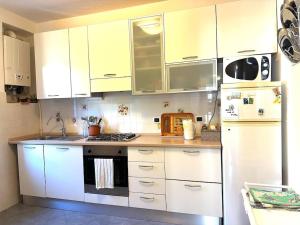 Una cocina con gabinetes blancos y un refrigerador blanco. en Casa Delfina, en Tellaro