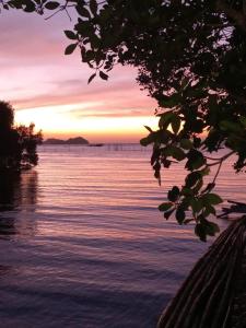 a sunset over the water with a pier in the background at CABRERA GUEST HOUSE exGREEN BAMBOO GUIMARAS in Nueva Valencia