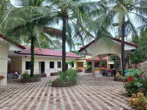 a courtyard with palm trees in front of a building at CABRERA GUEST HOUSE exGREEN BAMBOO GUIMARAS in Nueva Valencia