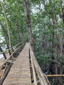 a wooden bridge in a forest with trees at CABRERA GUEST HOUSE exGREEN BAMBOO GUIMARAS in Nueva Valencia