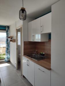 uma cozinha com armários brancos e um lavatório em Appartement résidence Acapulco vue panoramique port Argeles sur mer em Argelès-sur-Mer