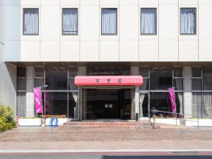 un edificio con un toldo rojo delante de él en Tabist Hotel Chouseikaku, en Yatsushiro