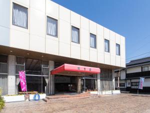 un gran edificio blanco con toldo rojo en Tabist Hotel Chouseikaku, en Yatsushiro