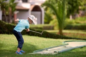 a young child swinging a club at a golf ball at Aldemar Knossos Royal in Hersonissos