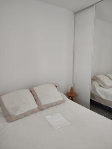 uma cama branca com duas almofadas em cima em Appartement résidence Acapulco vue panoramique port Argeles sur mer em Argelès-sur-Mer