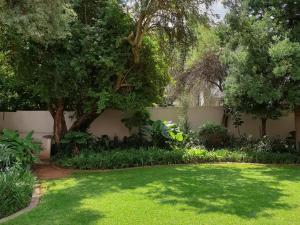 a garden with green grass and trees and a wall at Studio's@360onChurch in Pretoria