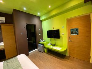 Zimmer mit einem Bett, einem TV und einer Tür in der Unterkunft Beauty House Homestay in Magong