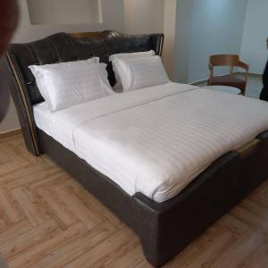 a bed with a black frame and white sheets and pillows at Wilsen Hotel Nansana in Kampala