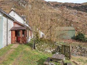 una vecchia casa con una panchina davanti di Stonefield Farm Cottage a Benmore