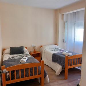 a bedroom with two beds and a window at Pensión Fornos in Caldas de Reis