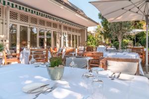 ein Restaurant mit weißen Tischen und einem Sonnenschirm in der Unterkunft Hotel-Restaurant Erbprinz in Ettlingen