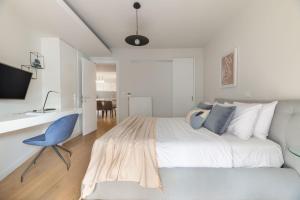 a white bedroom with a bed and a blue chair at Elegant 2BR Apartment in Kolonaki by UPSTREET in Athens