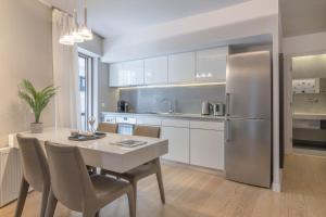 a kitchen with a table and a stainless steel refrigerator at Elegant 2BR Apartment in Kolonaki by UPSTREET in Athens