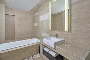 a bathroom with a sink and a tub and a mirror at Courtyard by Marriott Bali Nusa Dua Resort in Nusa Dua
