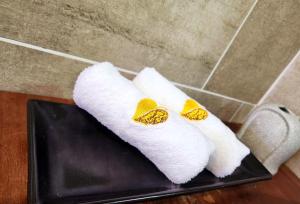 zwei weiße Handtücher mit gelben Schalen auf einem schwarzen Tablett in der Unterkunft Uptown Eco Hotel in Kuala Terengganu