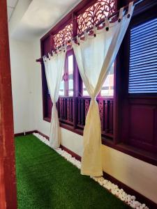 a room with green carpet and windows with curtains at Uptown Eco Hotel in Kuala Terengganu