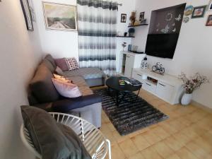 ein Wohnzimmer mit einem Sofa und einem TV in der Unterkunft Apartments Ruza vjetrova in Postira