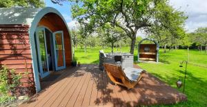 eine Holzterrasse mit einer Bank und einer Feuerstelle in der Unterkunft Orchard Farm Luxury Glamping in Glastonbury