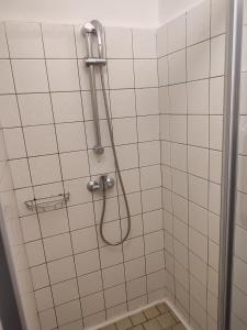 um chuveiro com uma mangueira numa casa de banho em azulejos brancos em BEST Hotel Garni em Olomouc