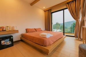 een slaapkamer met een bed en een groot raam bij Melody Retreat - Venuestay in Hòa Bình