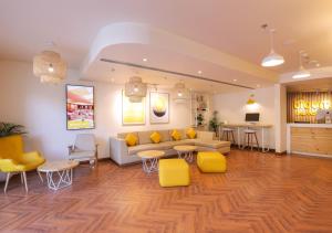 a living room with a couch and yellow chairs at Bloom Hotel - Jalandhar in Jalandhar